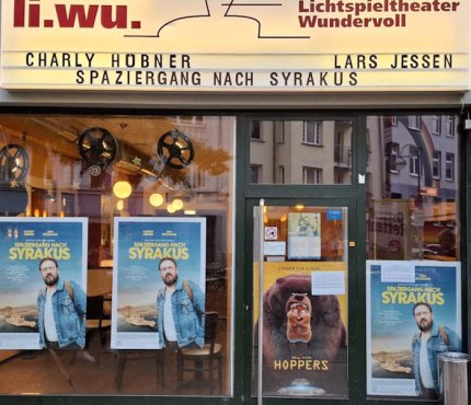 Eingang des li.wu. Metropol mit Leuchtreklame zur Premiere und Postern